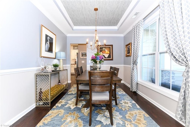 dining area with a raised ceiling, dark hardwood / wood-style floors, and an inviting chandelier