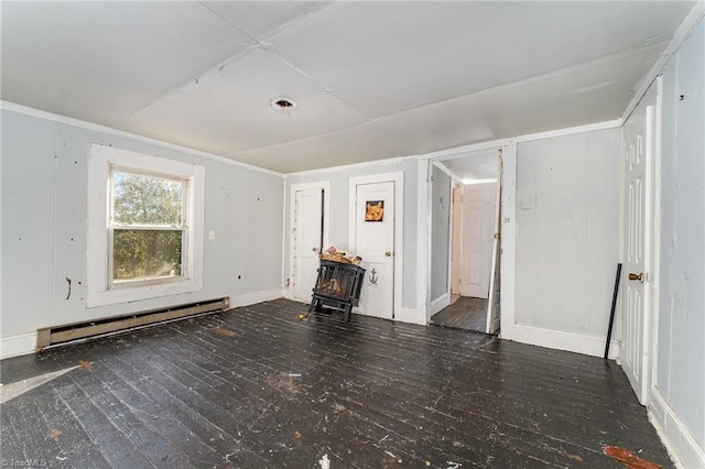 empty room with a wood stove, dark wood-type flooring, and a baseboard radiator