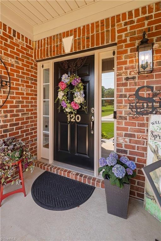 property entrance with brick siding and a porch