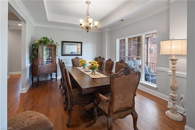 dining area featuring a chandelier, wood finished floors, a raised ceiling, baseboards, and ornamental molding