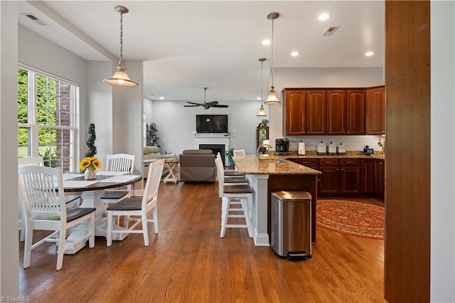 kitchen with a peninsula, open floor plan, a breakfast bar, a fireplace, and dark wood-style flooring