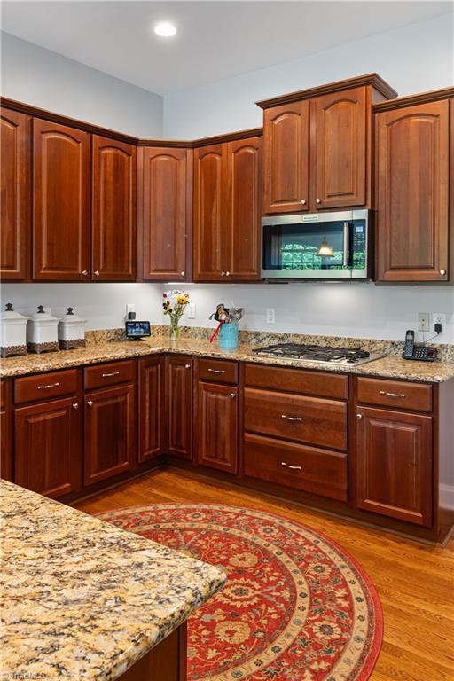 kitchen featuring appliances with stainless steel finishes, light wood finished floors, light stone counters, and recessed lighting