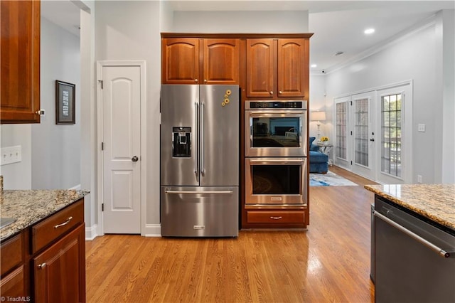 kitchen with appliances with stainless steel finishes, light wood finished floors, light stone counters, crown molding, and recessed lighting