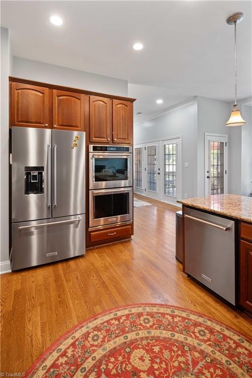 kitchen featuring appliances with stainless steel finishes, light wood finished floors, decorative light fixtures, light stone counters, and recessed lighting