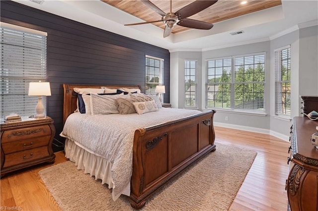 bedroom featuring a tray ceiling, baseboards, light wood finished floors, crown molding, and wood ceiling