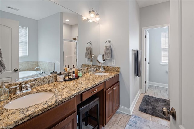 bathroom with a bath, double vanity, baseboards, and tile patterned floors