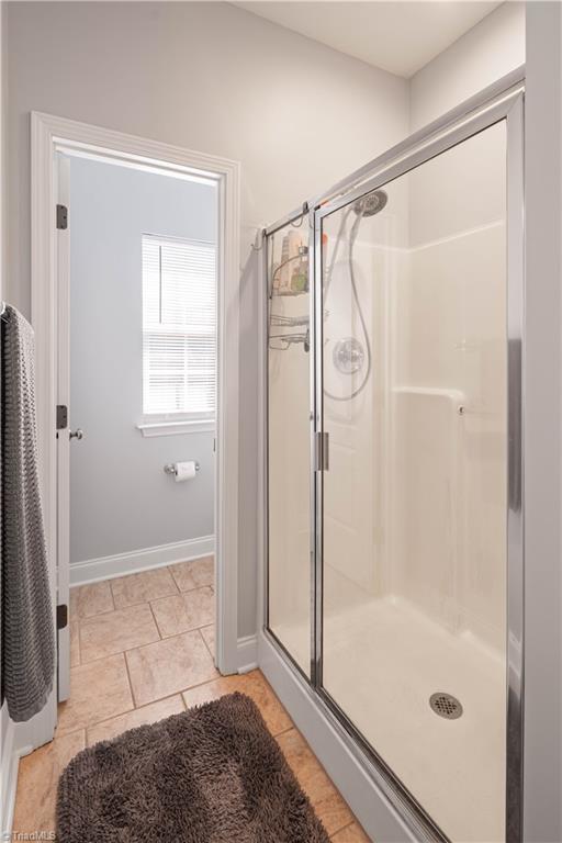 bathroom with a shower stall, baseboards, and tile patterned floors