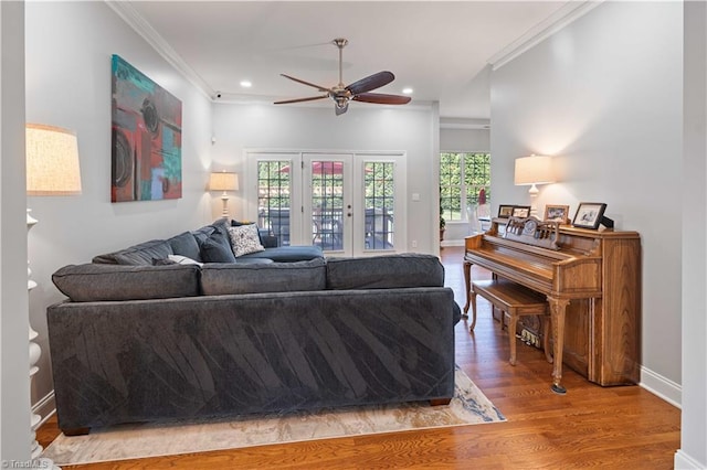 living area with ceiling fan, ornamental molding, wood finished floors, plenty of natural light, and baseboards