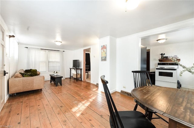 living area with ornamental molding, baseboards, visible vents, and light wood finished floors