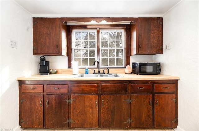 kitchen with black microwave, light countertops, and a sink