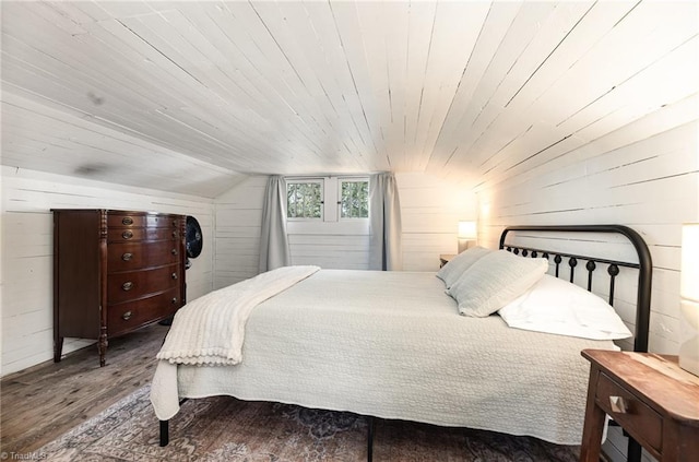 bedroom featuring vaulted ceiling, wood walls, wooden ceiling, and wood finished floors