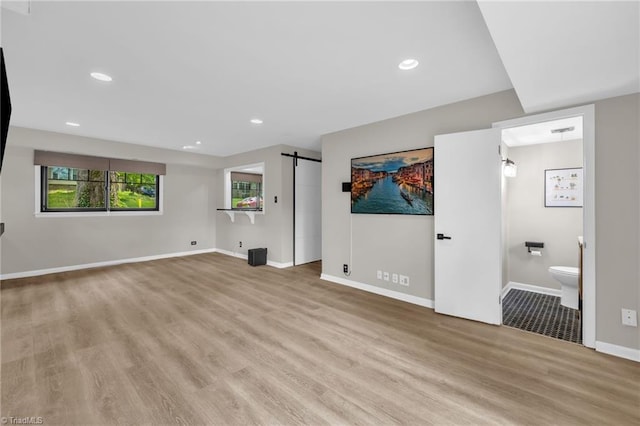 1508 Lafayette Ct, Greensboro, NC 27408 - unfurnished living room with light wood-style flooring, baseboards, a barn door, and recessed lighting