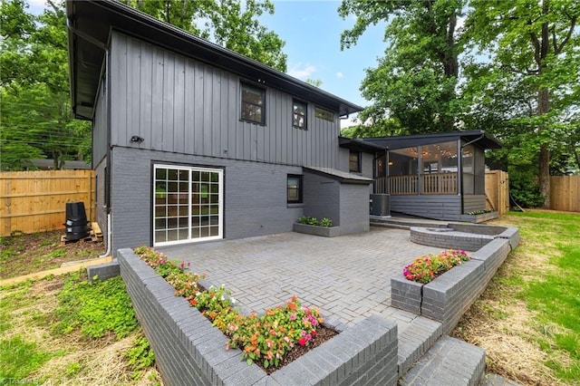 1508 Lafayette Ct, Greensboro, NC 27408 - rear view of house featuring board and batten siding, a sunroom, a patio area, and brick siding
