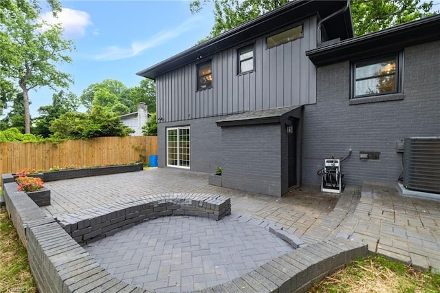 1508 Lafayette Ct, Greensboro, NC 27408 - back of house featuring board and batten siding, brick siding, central AC, and a patio area