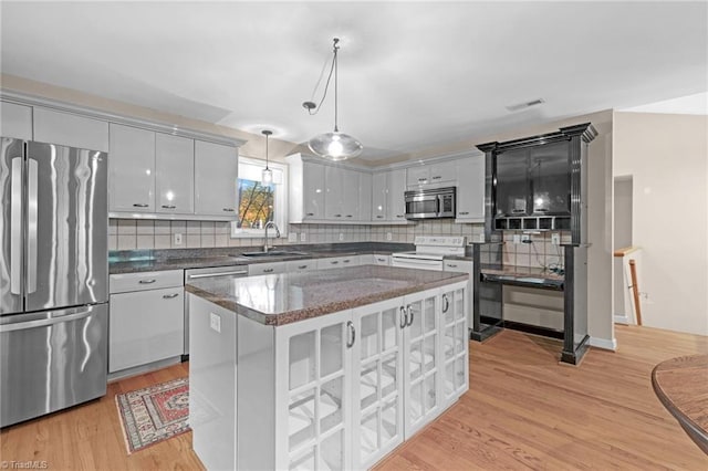1134 Edwards Farm Rd, King, NC 27021 - kitchen featuring stainless steel appliances, a sink, light wood finished floors, backsplash, and decorative light fixtures