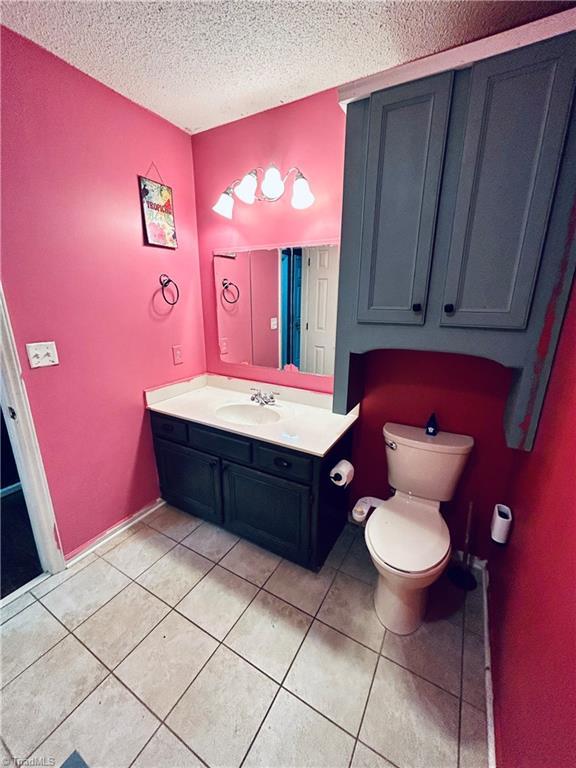 bathroom with vanity, toilet, a textured ceiling, and tile patterned flooring