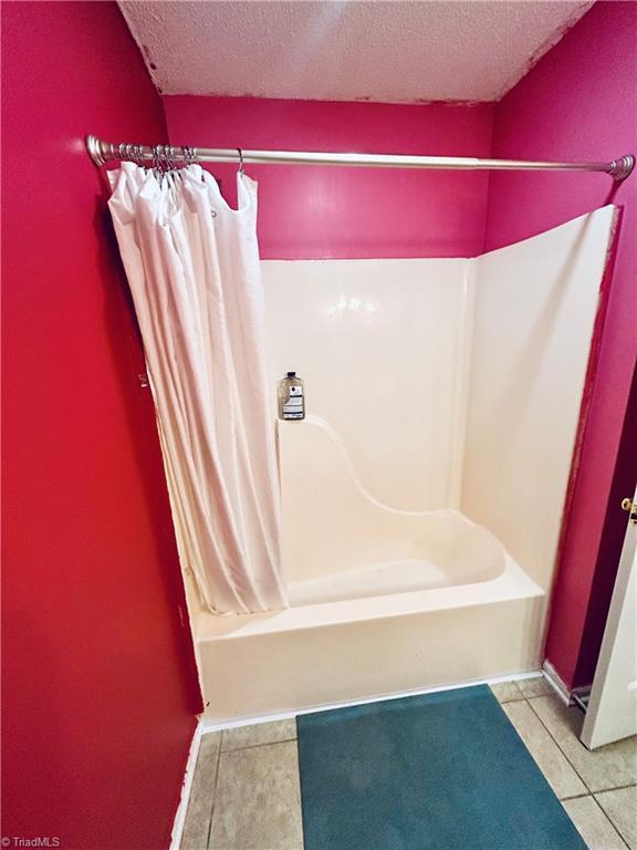 bathroom featuring a textured ceiling, shower / bath combo, and tile patterned flooring