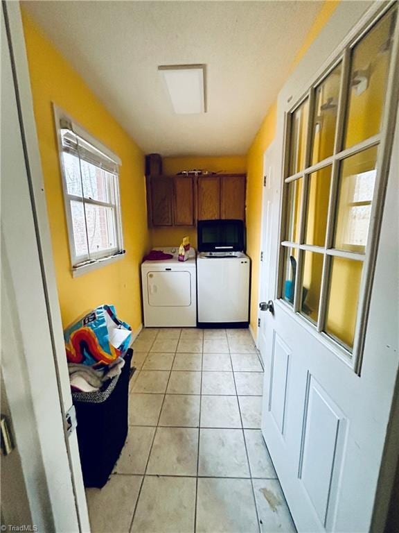 laundry area featuring light tile patterned floors, cabinets, and washer and dryer