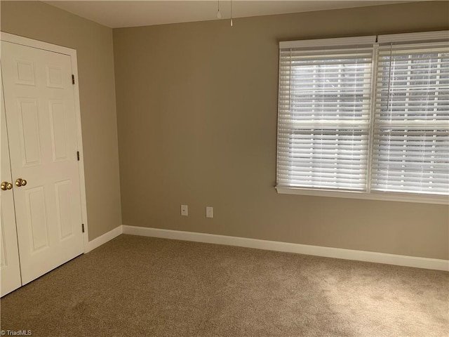 spare room featuring carpet flooring and baseboards