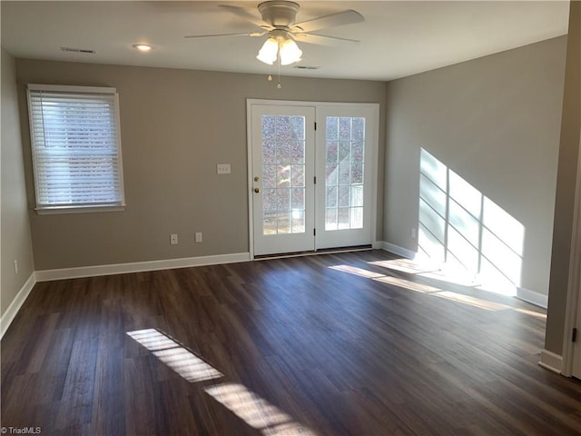 interior space with visible vents, baseboards, a ceiling fan, and dark wood-style flooring