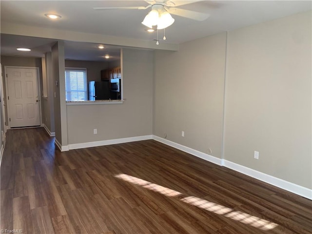 unfurnished room featuring a ceiling fan, baseboards, and dark wood-style flooring