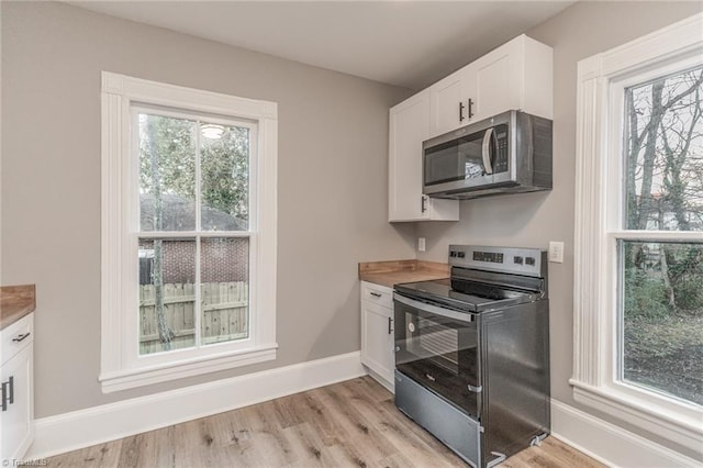 kitchen featuring white cabinetry, appliances with stainless steel finishes, wood counters, and light hardwood / wood-style floors