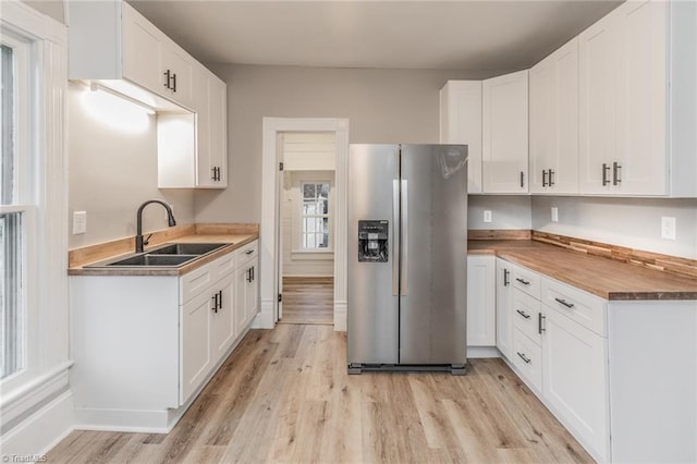 kitchen with white cabinetry, sink, and stainless steel fridge