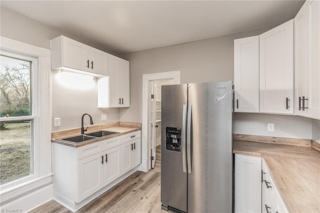 kitchen featuring sink, white cabinets, light wood-type flooring, and stainless steel fridge with ice dispenser