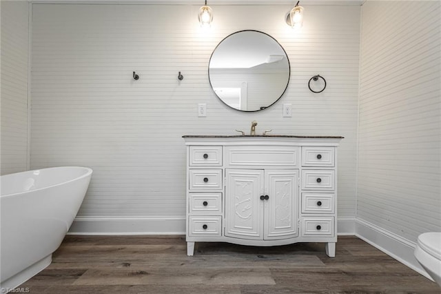 bathroom with a bath, vanity, hardwood / wood-style floors, and toilet