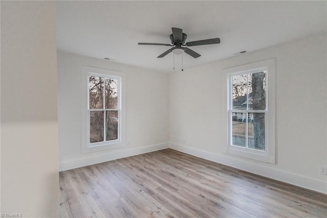 empty room featuring ceiling fan, a wealth of natural light, and light wood-type flooring