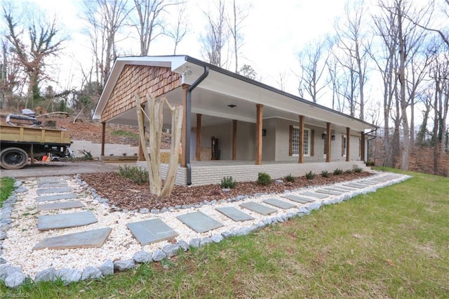 view of side of home with covered porch and a yard