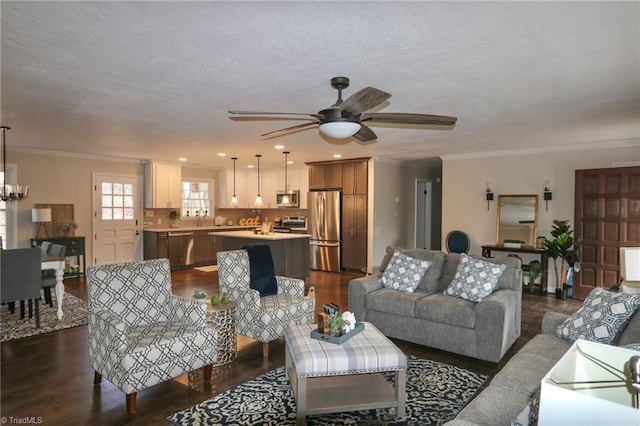 living room featuring ceiling fan with notable chandelier, dark hardwood / wood-style floors, ornamental molding, and sink