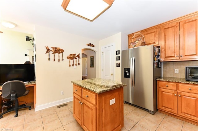 226 Marshview Cir, Angier, NC 27501 - kitchen featuring a center island, light stone counters, light tile patterned flooring, arched walkways, and stainless steel refrigerator with ice dispenser