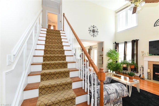 226 Marshview Cir, Angier, NC 27501 - stairway featuring a ceiling fan, wood finished floors, a towering ceiling, and a tiled fireplace