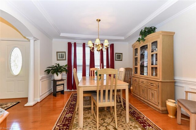 226 Marshview Cir, Angier, NC 27501 - dining room with wainscoting, a chandelier, light wood-style floors, ornamental molding, and ornate columns