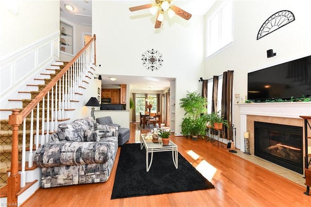 226 Marshview Cir, Angier, NC 27501 - living room featuring stairs, wood finished floors, ceiling fan, a towering ceiling, and a fireplace