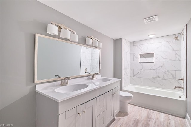 full bathroom featuring vanity, tiled shower / bath combo, and toilet