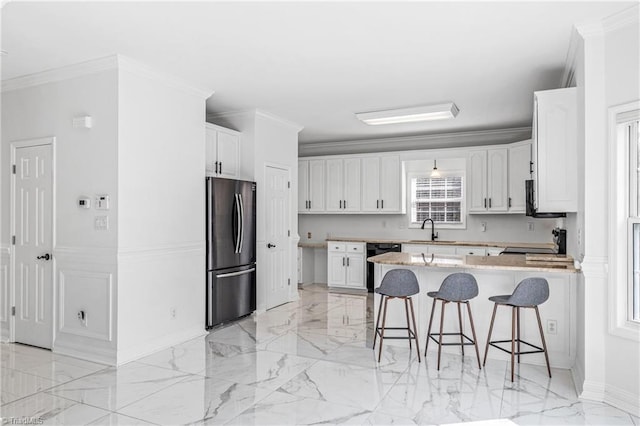 kitchen featuring sink, a breakfast bar area, stainless steel refrigerator, ornamental molding, and white cabinets