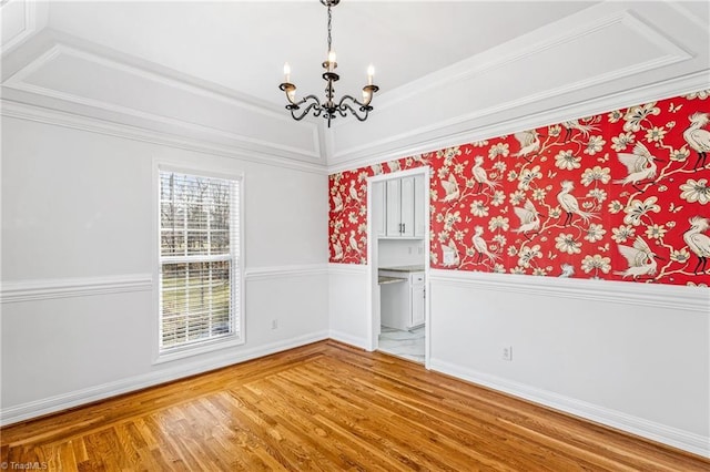 spare room with an inviting chandelier, hardwood / wood-style floors, and ornamental molding