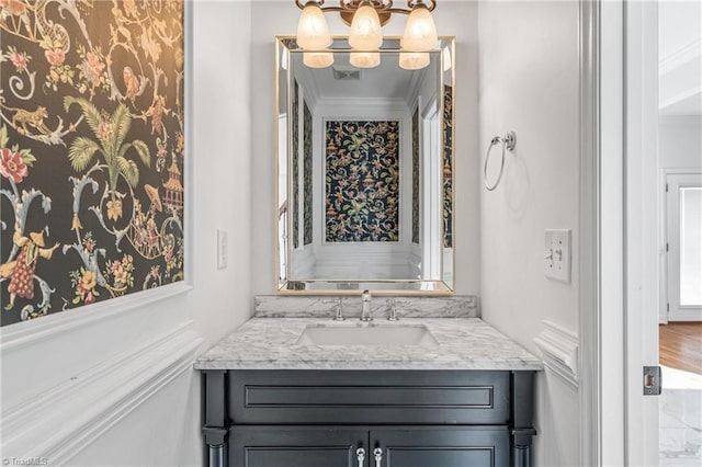 bathroom with crown molding, vanity, and a notable chandelier