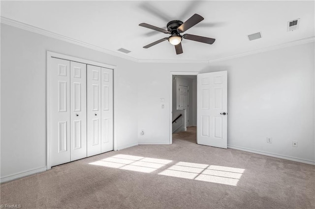 unfurnished bedroom featuring ornamental molding, light colored carpet, ceiling fan, and a closet