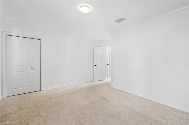 unfurnished bedroom with crown molding, light carpet, and a closet