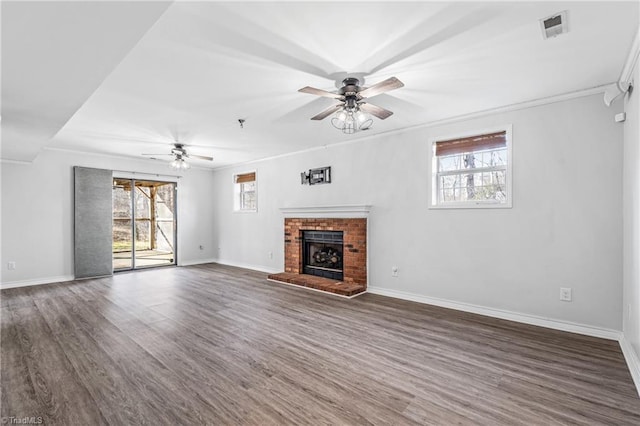 unfurnished living room featuring a fireplace, dark wood-type flooring, a wealth of natural light, and ceiling fan