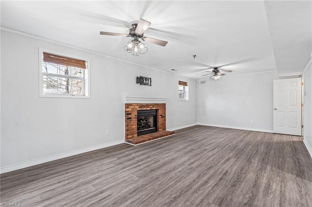 unfurnished living room featuring crown molding, a brick fireplace, dark wood-type flooring, and ceiling fan