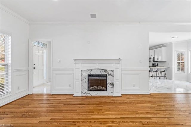 unfurnished living room featuring ornamental molding, a premium fireplace, and light hardwood / wood-style floors