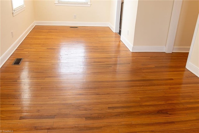 unfurnished room with wood finished floors, visible vents, and baseboards