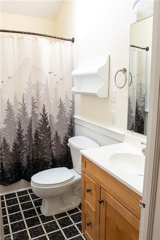 bathroom with a shower with shower curtain, toilet, and vanity