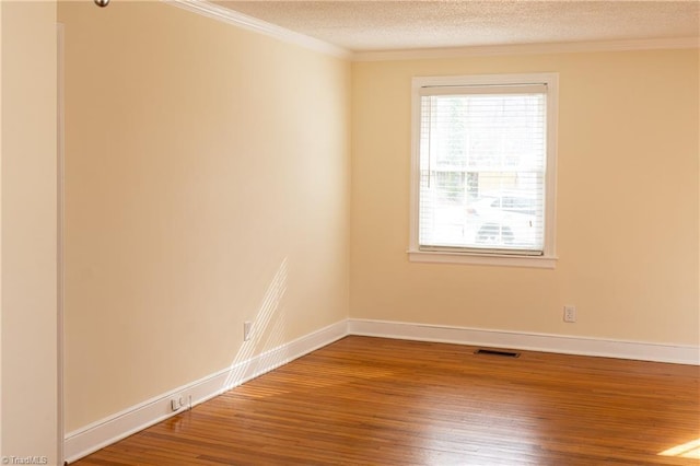 spare room with baseboards, a textured ceiling, wood finished floors, and ornamental molding