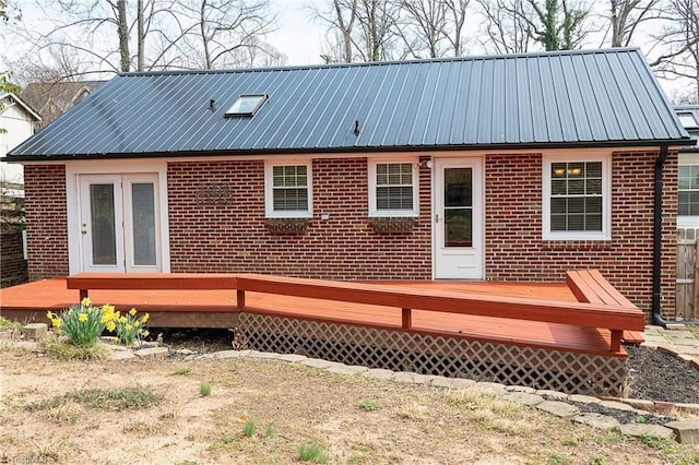 back of property with brick siding, a wooden deck, and metal roof