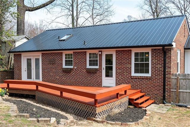 back of property with brick siding, french doors, a wooden deck, and fence